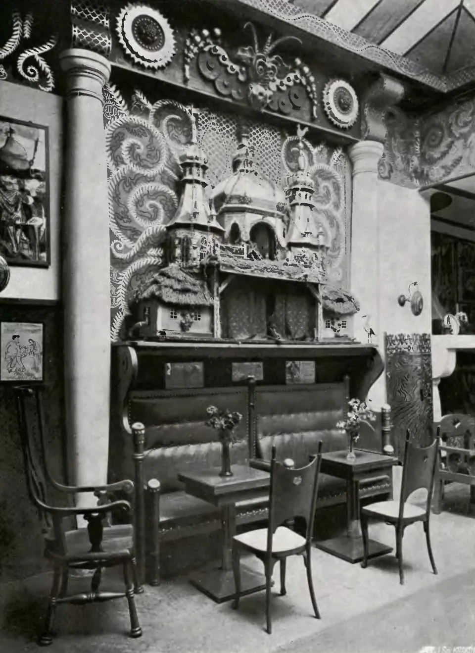 A black-and-white photograph of the Green Balloon puppet stage: towers and a thatched cottage against a swirling painted wall.